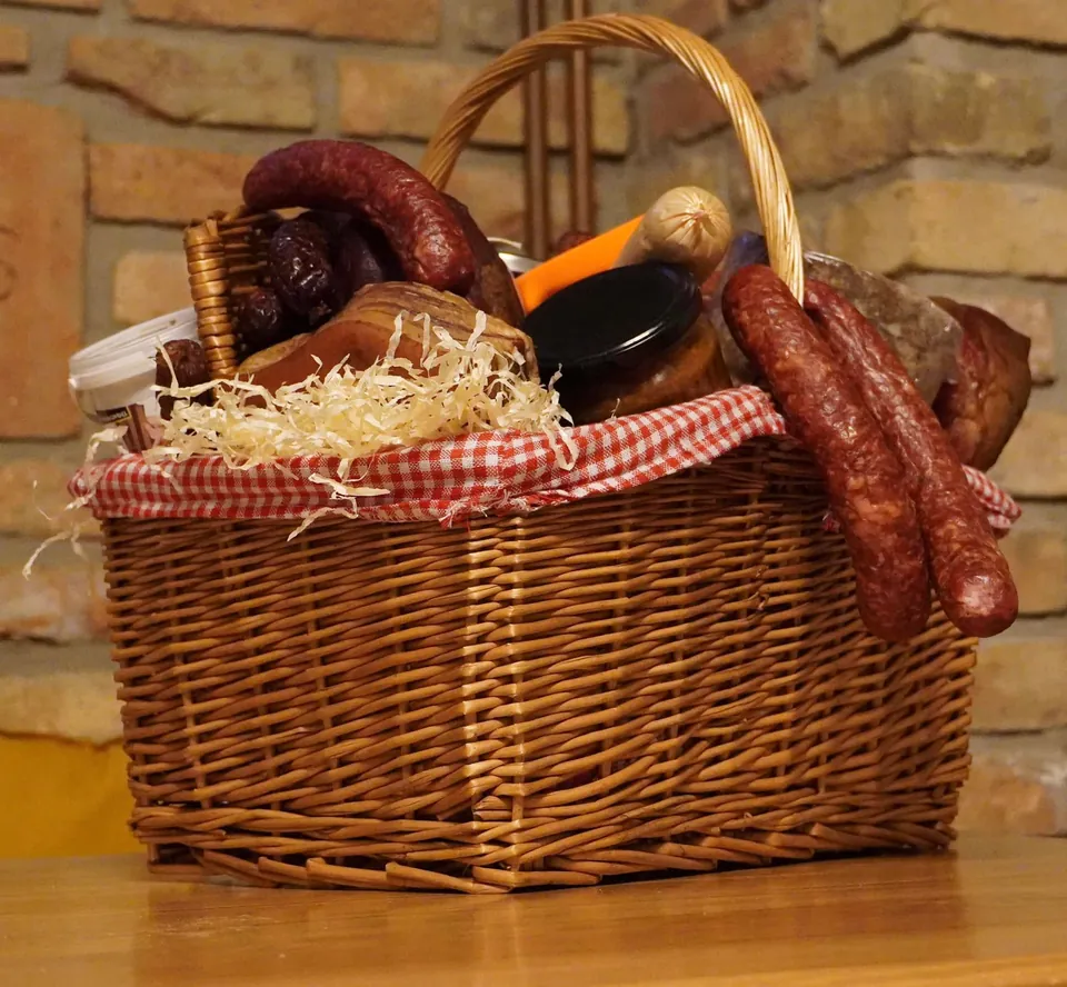 Proutěný koš s klobásami, uzeninami a sklenicemi